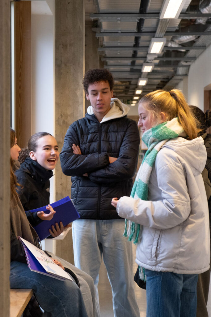 Leerlingen die op de gang met elkaar aan het babbelen zijn