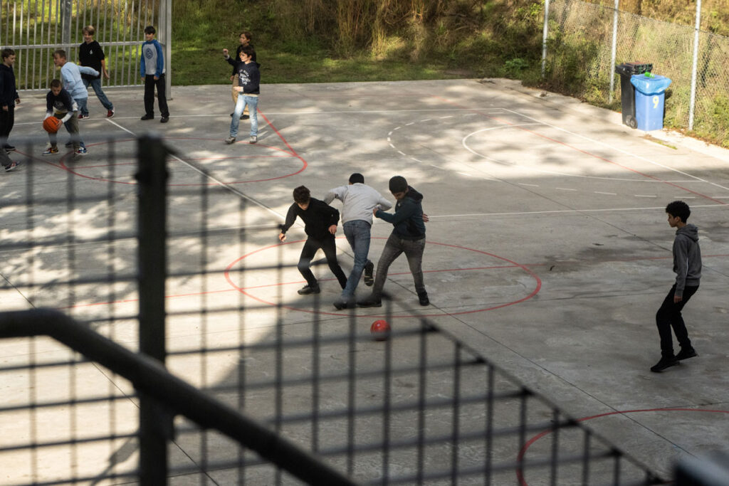 kinderen die aan het voetballen zijn op een voetbalpleintje